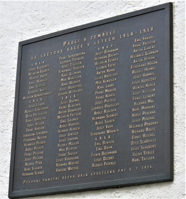 Plaque angebracht an einer Gebäudewand mit der Inschrift "Plaque für die Opfer des Holocaust" in einem dunklen Material mit einem dekorativen Rahmen.