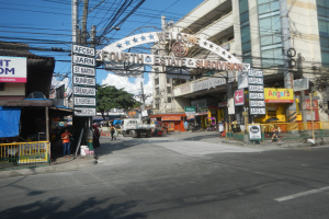 Eine belebte Stadtstraße mit Fahrzeugen, Fußgängern, Gebäuden und einem Schild mit der Aufschrift "Vierte Gewalt Unterabteilung" in der Mitte.