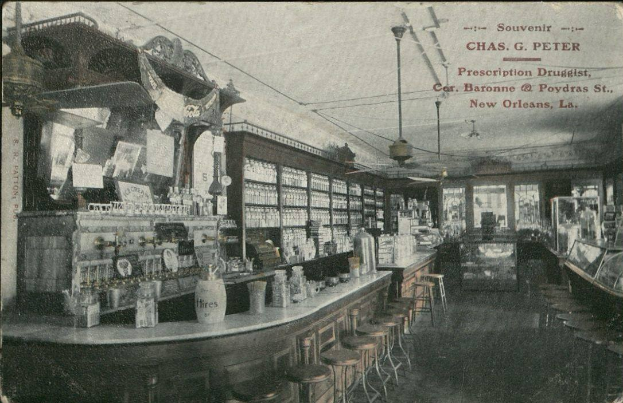 Schwarzes und weißes Foto eines alten Apothekeninneren in New Orleans, Louisiana, mit Hockern, Tischen mit Flaschen und Glasfenstern mit Text oben.