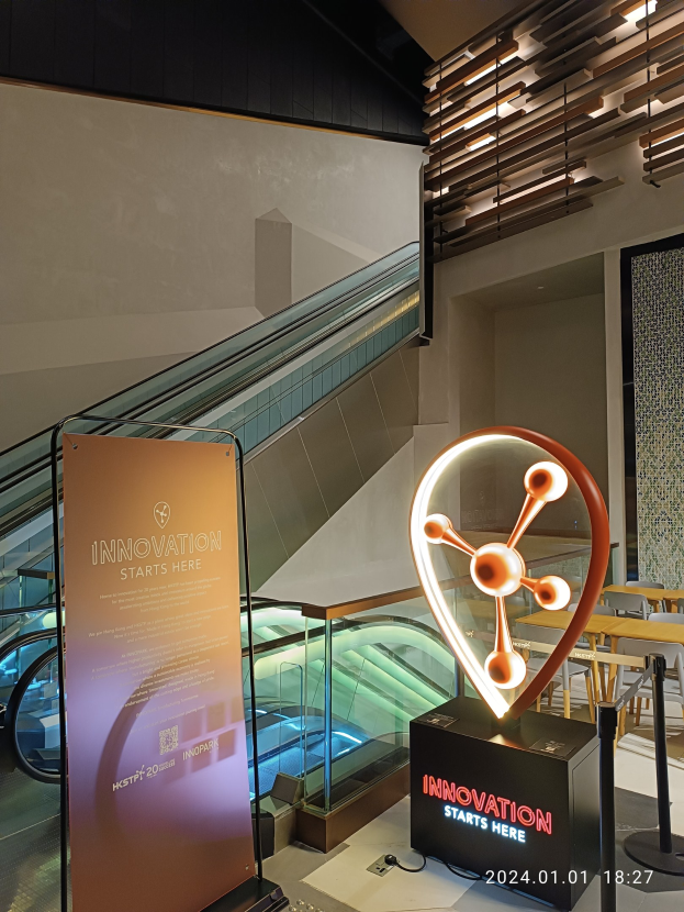 Großes Schild mit der Aufschrift "Innovation beginnt hier" in einem Gebäude mit einer Treppe im Hintergrund, Tische und Stühle auf der rechten Seite und ein Expo-Schild mit der Aufschrift "HSTP20 Expo" auf der linken Seite.