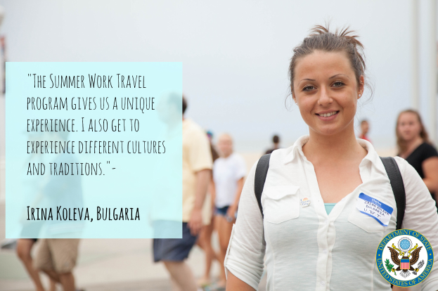 Eine Frau mit einer Tasche und einem Lächeln, umgeben von einer Gruppe von Menschen, die auf dem Boden gehen, mit Text auf der linken Seite, der lautet: "Das Sommerarbeitprogramm gibt uns eine einzigartige Erfahrung, ich erlebe auch verschiedene Kulturen und Traditionen - Irina Koleva, Bulgarien."