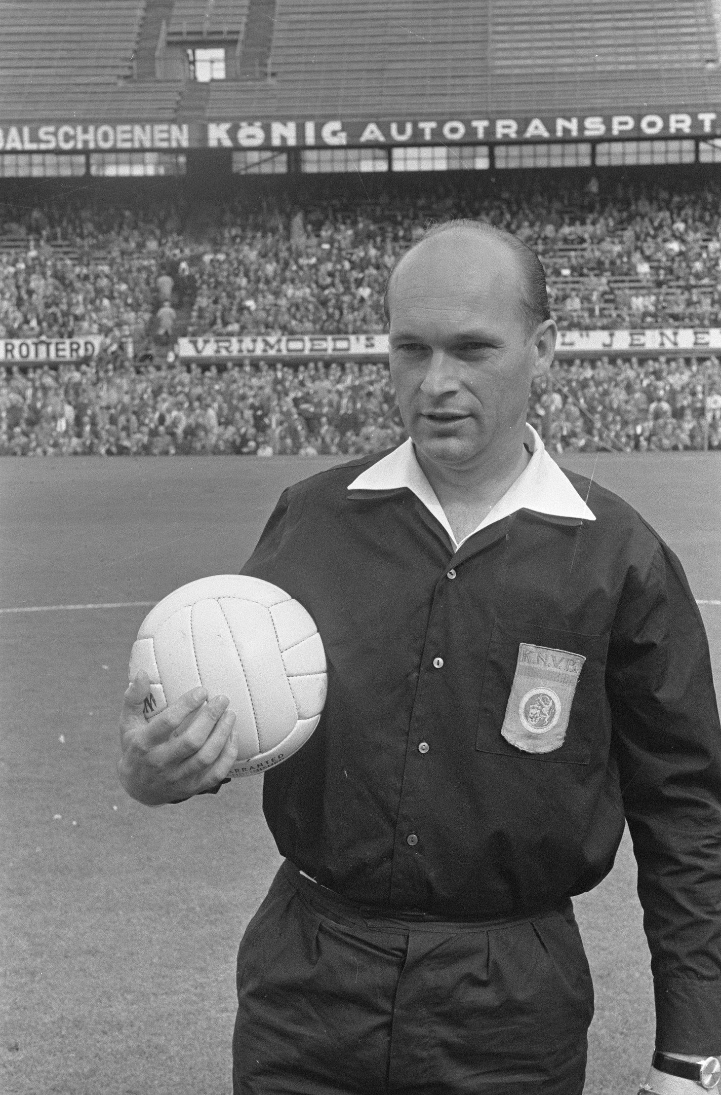 Schwarz-weiß-Foto eines Schiedsrichters, der einen Fussball auf einem Feld hält