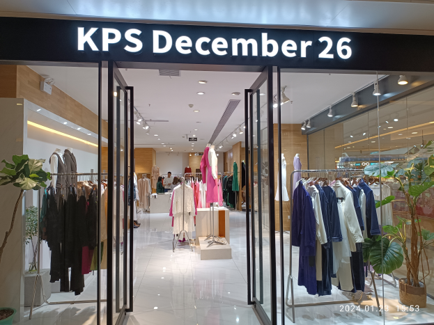 Das Innere eines KPS-Geschäfts am 26. Dezember in Singapur, mit Kleidung an Bügeln, bekleideten Schaufensterpuppen, Topfpflanzen, Glaswänden, Deckenlampen und einer Namensschilder mit Text, mit dem Boden unten sichtbar.