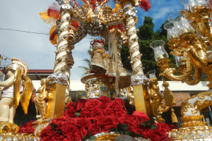 Ein Rosen- und Goldschmuck geschmückter Paradewagen mit Statuen und Blumen im Hintergrund.