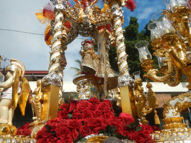 Ein Rosen- und Goldschmuck geschmückter Paradewagen mit Statuen und Blumen im Hintergrund.