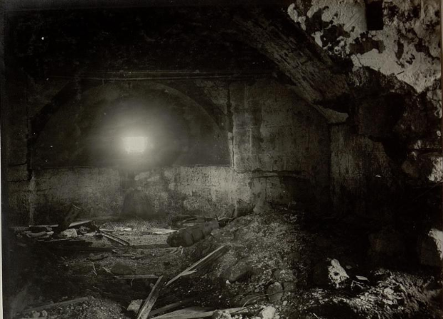 Altes Schwarz-Weiß-Foto eines zerfallenden Tunnels in den Berliner Mauertrümmern mit Schutt auf dem Boden und einem Licht am Ende.