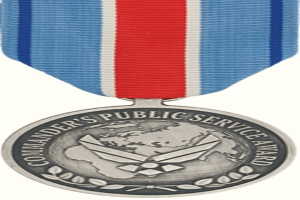 Eine silberne Medaille mit einer rot-weiß-blauen Schleife, auf der die Worte "Commander's Public Service Award" auf einem weißen Hintergrund stehen.