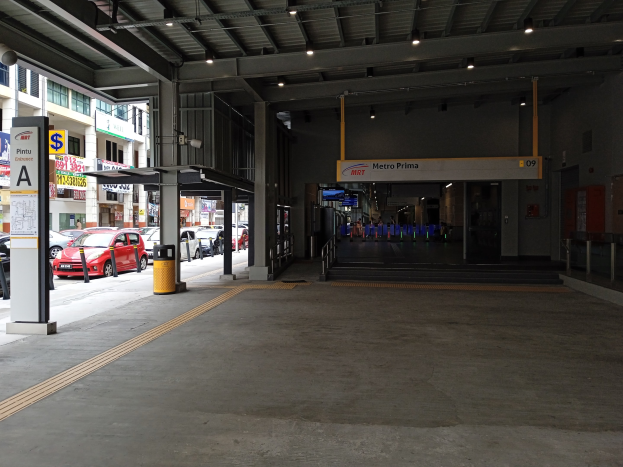 Leeres Parkhaus mit geparkten Autos, Betonpfeilern, Informationsschildern, Deckenbeleuchtung und Gebäuden mit Fenstern im Hintergrund.