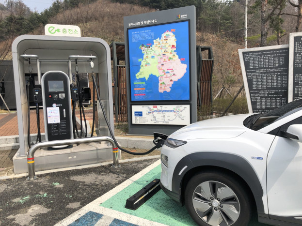 Elektroauto-Laden an einer Station umgeben von Bäumen in Seoul, Südkorea, mit Himmel im Hintergrund.