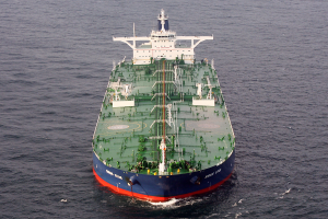 Ein großes grünes und blaues Öltankschiff treibt in der Mitte des Ozeans, umgeben von einer endlosen blauen Wasserfläche, auf der die Sonne glitzert.