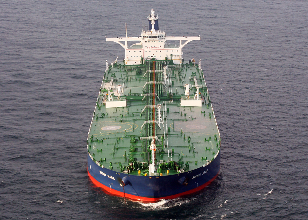 Ein großes grünes und blaues Öltankschiff treibt in der Mitte des Ozeans, umgeben von einer endlosen blauen Wasserfläche, auf der die Sonne glitzert.