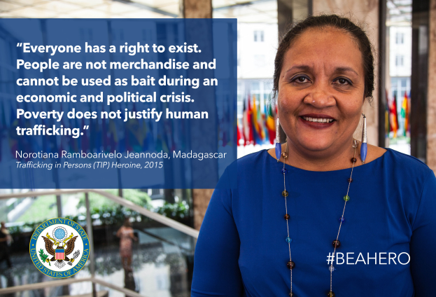 Eine Frau in einem blauen Kleid steht lächelnd vor einem Gebäude mit einem Zitat über Menschenrechte, umgeben von Menschen, Pflanzen und Flaggen, und einem Logo und Text auf der linken Seite.