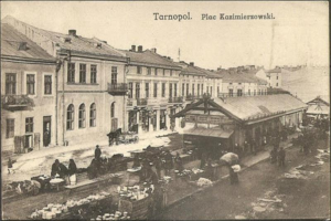 Schwarz-weiß-Foto eines belebten Marktes in Tarnopol, Polen, mit Menschen und Karren, Gebäuden mit Fenstern im Hintergrund und Text oben.
