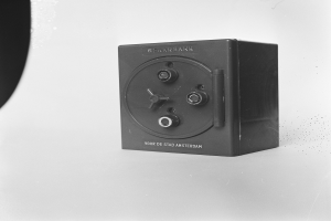 Ein Schwarz-Weiß-Foto eines rechteckigen Safe-Kastens auf einer weißen Oberfläche, mit einem Griff oben, einem Schloss an der Vorderseite und einem Schlüsselloch in der Mitte.