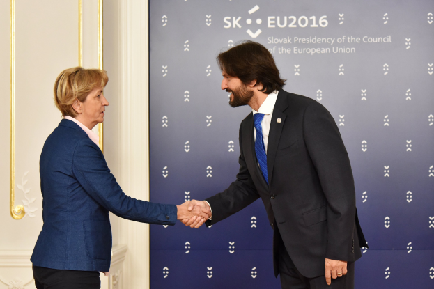 Bundeskanzlerin Angela Merkel und Bundespräsident Joachim Gauck schütteln sich lachend vor einem "EU-Gipfel"-Plakat die Hand.
