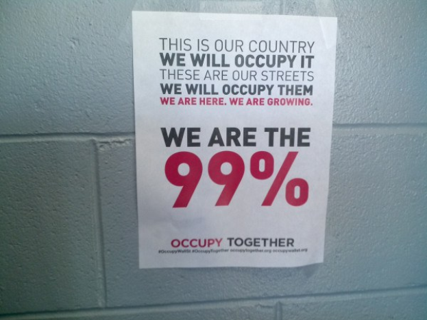 Plakat an einer Wand mit fettem schwarzem Text, der "Occupy Wall Street" und "Wir sind die 99%." lautet.