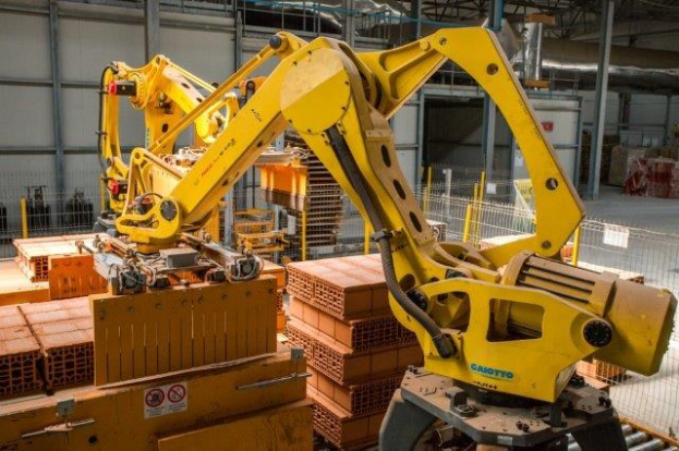 Ein großes Lager voller Numerous boxes, Kräne, ein Zaun, Pfosten und andere Gegenstände, mit einer Wand im Hintergrund, die eine industrielle Umgebung anzeigt.